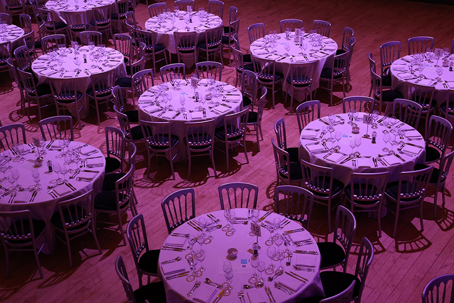 A room filled with round dinner tables with dimmed lighting