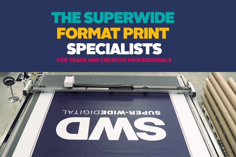 A screen shot of the Super-Wide Digital website featuring the words 'The Superwide Format Print Specialists' in bright colours and bold font with an ariel view of a wide-format printer printing a dark blue banner with white text on top with the letters 'SWD'