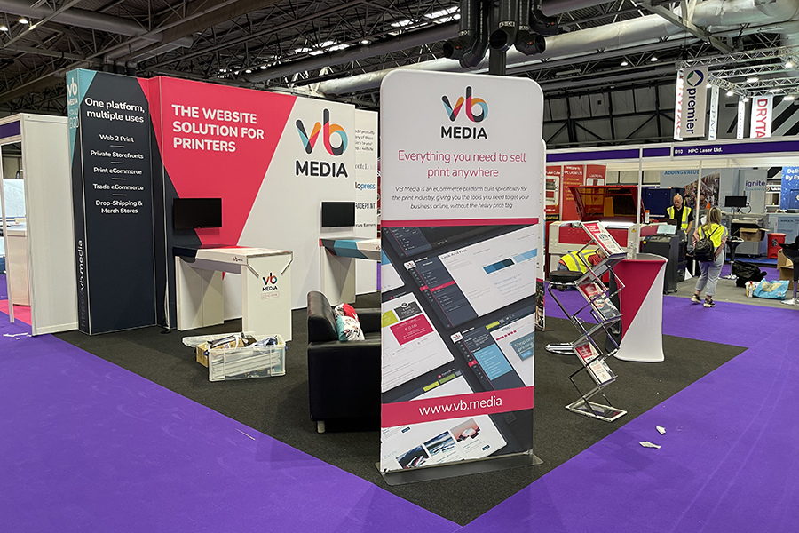 The VB Media stand at The Print Show 2023, the stand has examples of signage graphics and the floor is purple